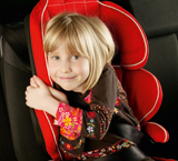 Niña sentada en el asiento trasero de un coche con una sillita del Grupo II/III